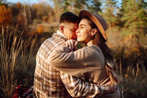 Couple in love rests and walks together in the autumn park. Stylish man and woman enjoy autumn weather. Concept of love, relationships, relaxation.