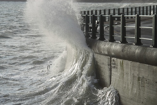 The sea waves crashing against the pier wall