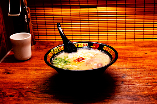 A bowl of ramen, traditional noodle in broth, served in a small restaurant in Tokyo, Japan.