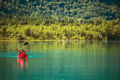 Happy Traveler Inside Red Canoe on a Glacial Lake with His Hands Up