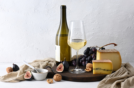 Still life with white wine, cheese and fruits