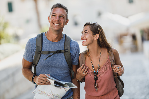 Cheerful couple in love having fun and enjoying summer vacation while walking and exploring a Mediterranean city.