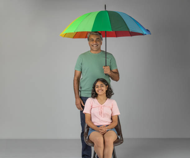 istock Smiling father holding umbrella while standing with daughter against white background 1636206283