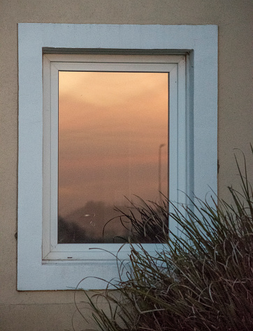 Sunset reflected in the window of a house