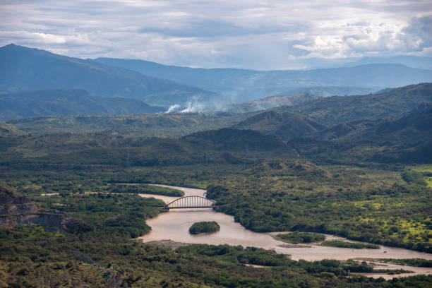 Colombian river in a landscape between mountains and forest. Aerial view of an iron bridge that crosses a river in a Colombian landscape madalena stock pictures, royalty-free photos & images