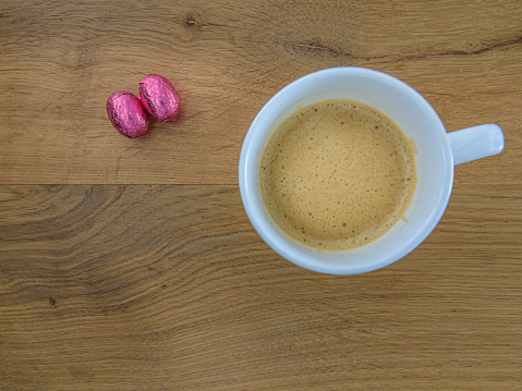 two chocolate easter eggs and a coffee cup on an oak background