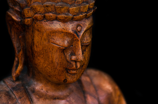 wooden buddha statue on black background closeup