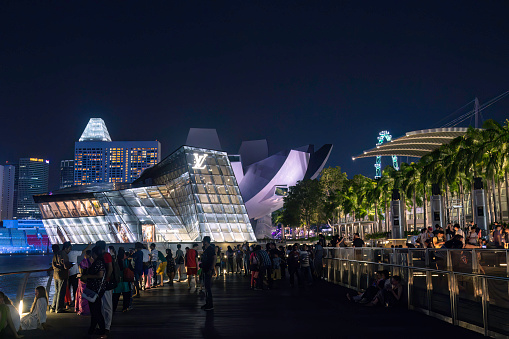 Singapore, Singapore, September 12th, 2016. People attending the laser show at night at the Marina Bay, with the city shopping mall and financial district in the background