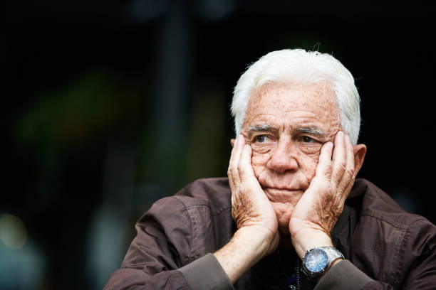 istock Elderly man sits, head in hands, looking unhappy and thoughtful 1636314595