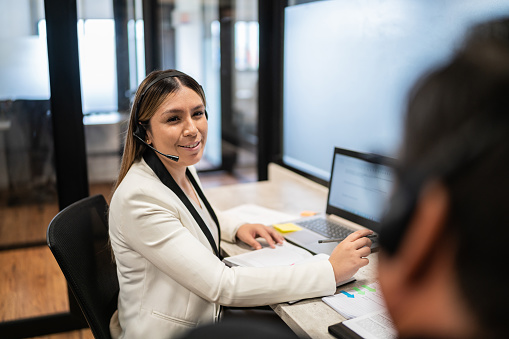 Young woman talking with her coworker while working on the call center at office