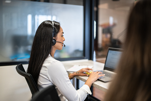 Female security guard operator talking on the phone while working at the workstation with multiple displays Security guards working on multiple monitors. High quality photo