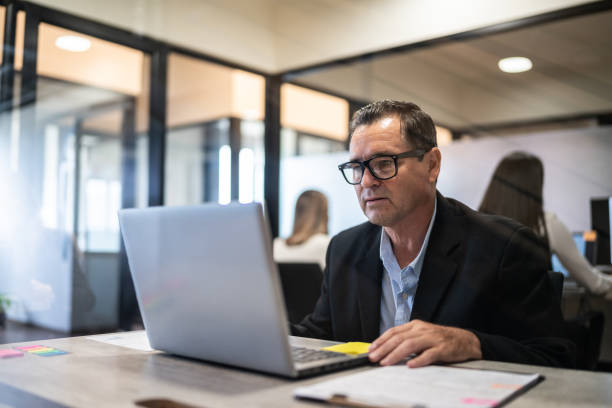 istock Mature businessman working using a laptop at office 1636331452