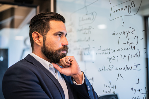 Businessman analyzing strategy on mirror at office