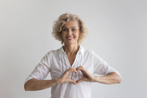 istock Happy pretty mature lady making heart shaped fingers 1636343367