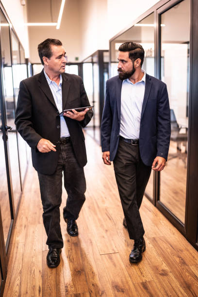 istock Businessmen walking and talking through the office 1636356297