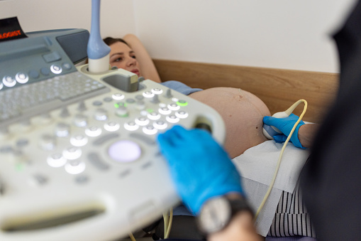 9 months pregnant woman having ultrasound with her gynecologist