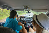 A husband and wife are traveling in their minivan, driving along a forest road. View from the salon of the bear. A beautiful couple travels during a vacation by car around the country.