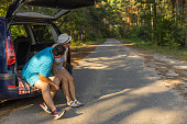 Copyspace. A man and a woman travelers sit with an open trunk of a car on a forest dog and look towards the empty space for an inscription. The concept of travel by car.