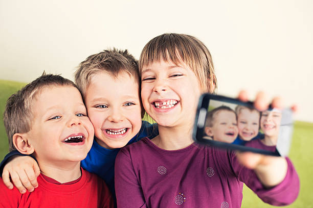 crianças tirando foto com telefone celular - embracing smiling gap children only - fotografias e filmes do acervo