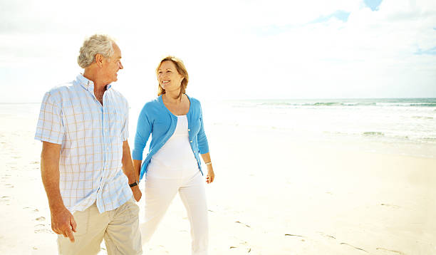 A happy senior couple walking on the beach holding hands