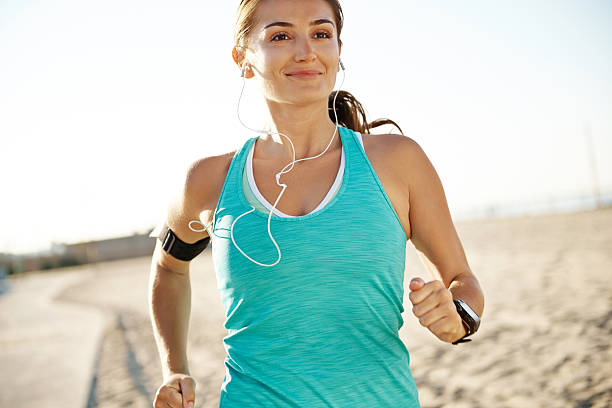 istock A smiling woman running while wearing earphones 163639110