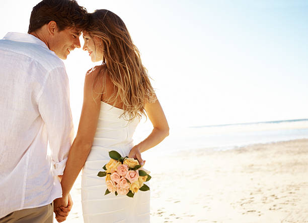 joven pareja en la playa - boda playa fotografías e imágenes de stock