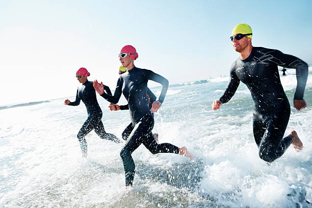 Training to win A group of athletes competing in a triathlon wetsuit stock pictures, royalty-free photos & images