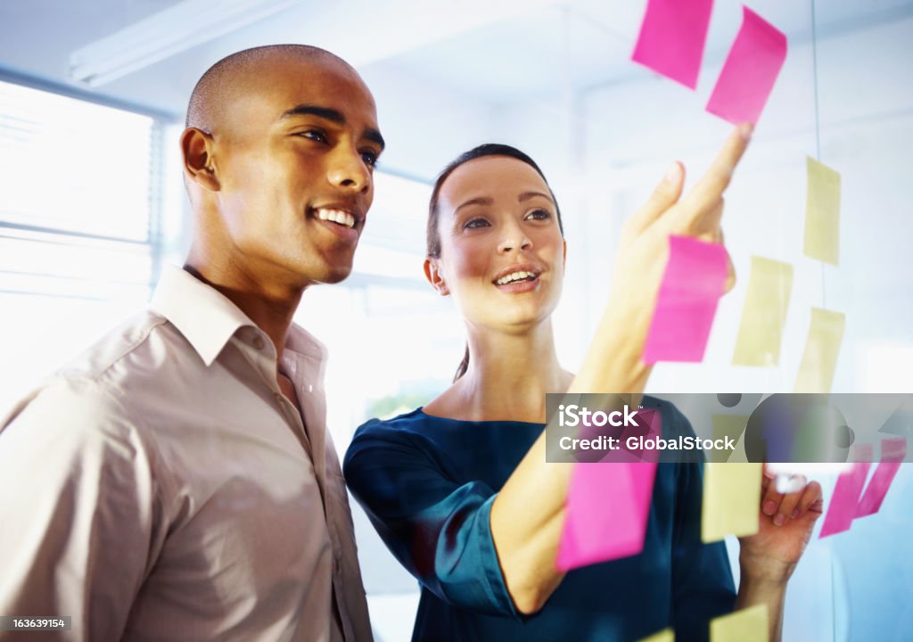 Many hands lighten the load Two colleagues brainstorming ideas with post-its Adhesive Note Stock Photo