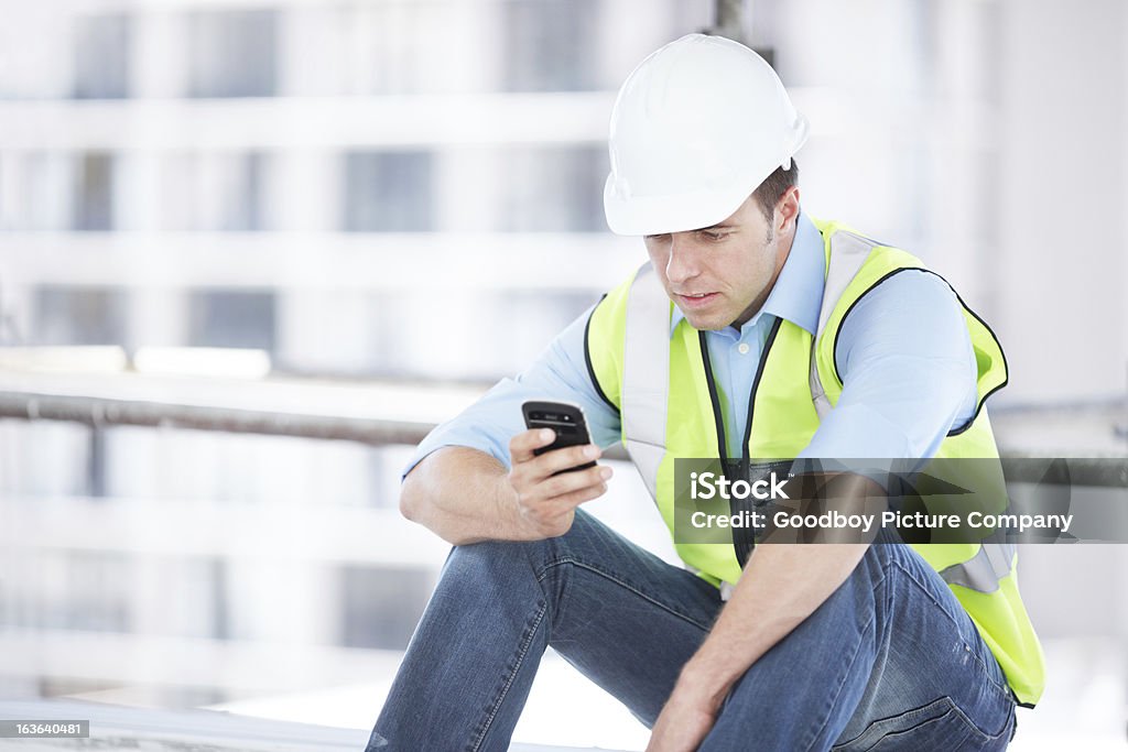 Modern technology keeping you in the know A young engineer typing a message on his mobile phone while at a construction site Construction Worker Stock Photo