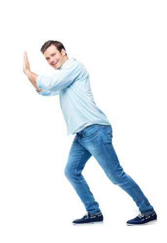 A casual young man pushing against something while isolated on a white background