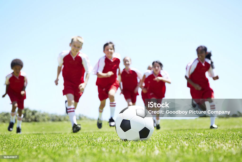 Attacking as a team A mixed-gender soccer team playing a football match Kids' Soccer Stock Photo