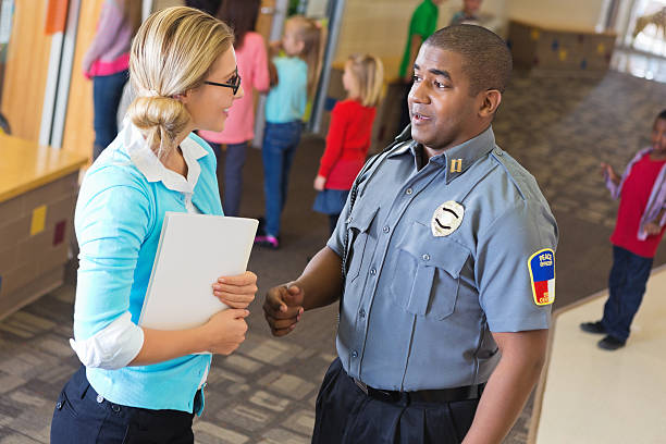 istock Police officer explaining something to teacher outside her classroom 163641119