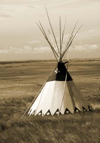 A majestic tipi sitting in the grasslands of an expansive prairie. Sepia toned.