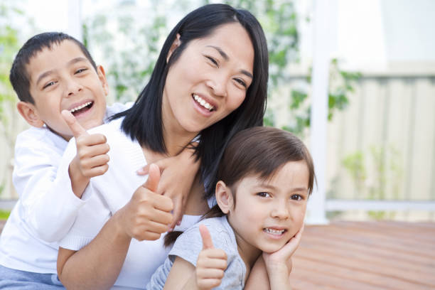 istock Mother and children sitting on deck putting thumbs up 163641523