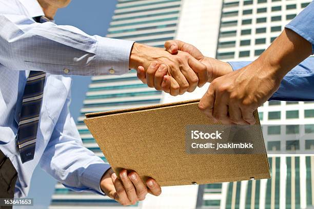 Business Men Handshaking And Sharing File Report In Financial District Stock Photo - Download Image Now