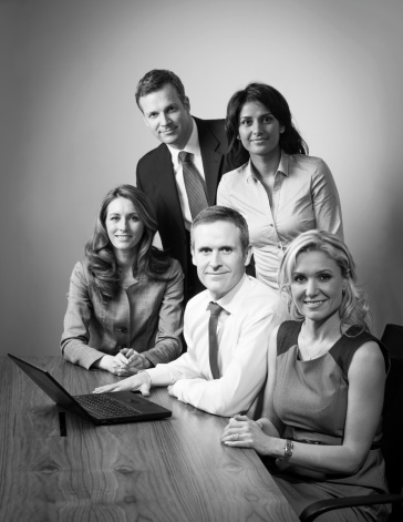 Business team portrait in meeting room. Black and white looking to camera.