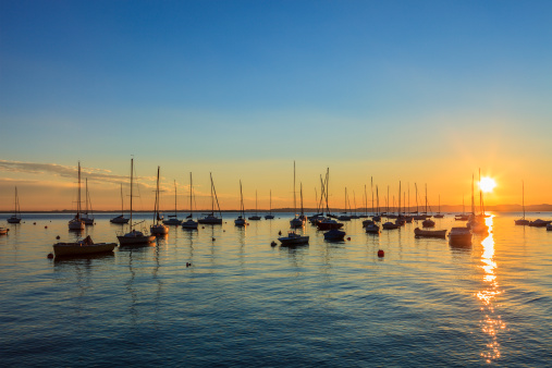 Sailboats moored in the natural harbor of Garda at sunset. Garda is one of the beautiful towns on the shores of Lake Garda, the largest Italian lake and a major tourist destination.