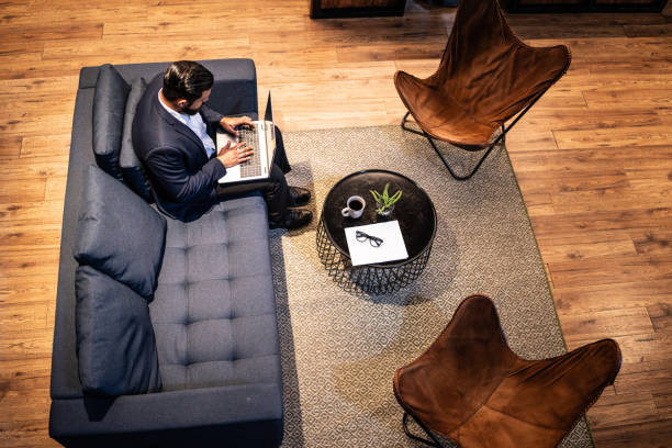 istock High angle view of a businessman working using laptop sitting on sofa while waiting at waiting room 1636422533