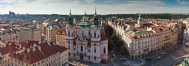 St Nicholas Church, Prague Magnificent baroque St Nicholas Church (1737), St Vitus Cathedral and rooftops bathed in warm sunlight in the magical city of prague. Stitched panoramic image detailed when viewed large. st nicholas church prague stock pictures, royalty-free photos & images
