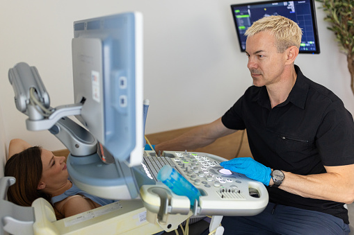 Obstetrician doing sonography exam to a pregnant woman