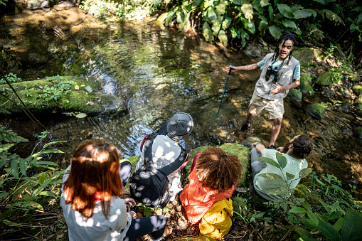 Tourist guide explaining to a group of friends during hiking in the forest