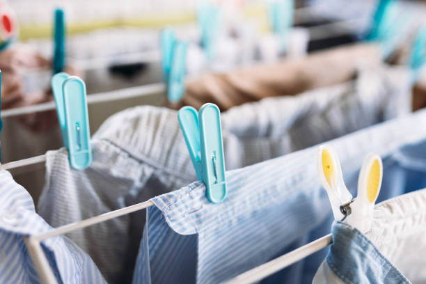 istock Clean laundry hanging on drying rack indoors, Freshly washed clothes drying on drying rack with color clothespins 1636467664