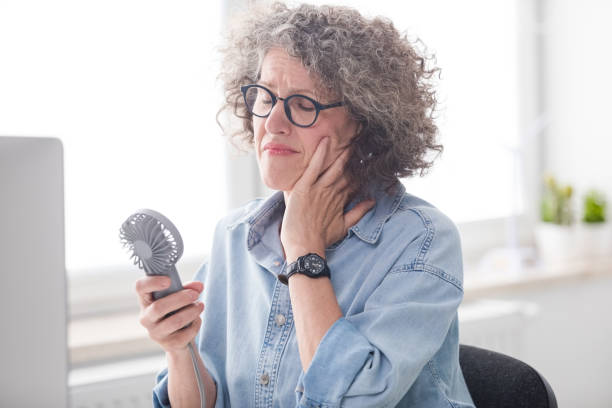 Menopausal woman having a hot flash at the office