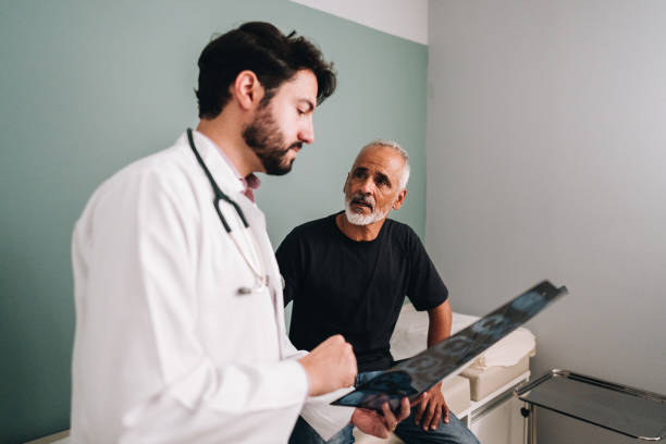 médico hablando con su paciente mientras muestra una imagen de rayos x en el consultorio de un médico - x ray image radiologist examining using voice fotografías e imágenes de stock