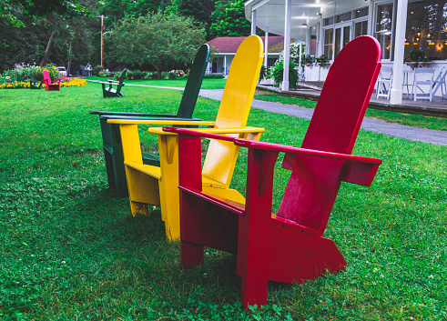 Red Adirondack-style chair on green grass in public park, Governors Island, New York City. Summer weekends, relaxation. Things to do in New York City.