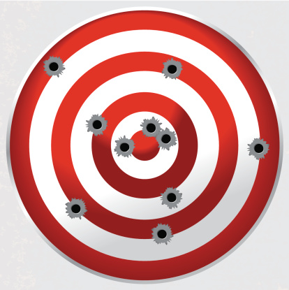 Red and white shooting range gun target shot full of bullet holes. File is layered for easy separation of bullet holes, target, and background.