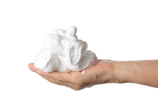 Close-up shot of shaving foam on the hand against white background.