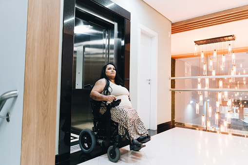 Wheelchair mature woman leaving elevator on a hospital