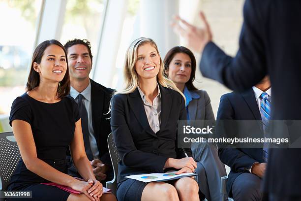An Audience Of Business People Smiling At A Presenter Stock Photo - Download Image Now