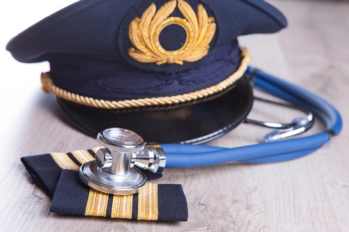 Close up of an airplane pilot equipment hat and epaluetes with doctor's stethoscope. Conceptual image of medical exam.
